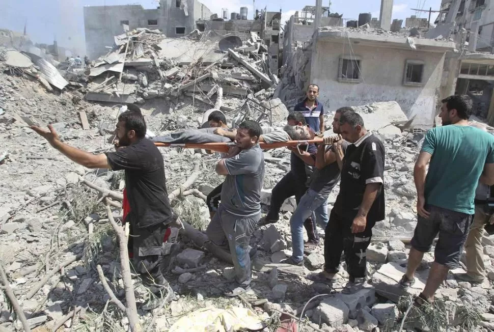 EN BEIT HANOUN. Palestinos trasladan un cadáver que encontraron entre los escombros de una vivienda, destruida por los bombardeos. reuters
