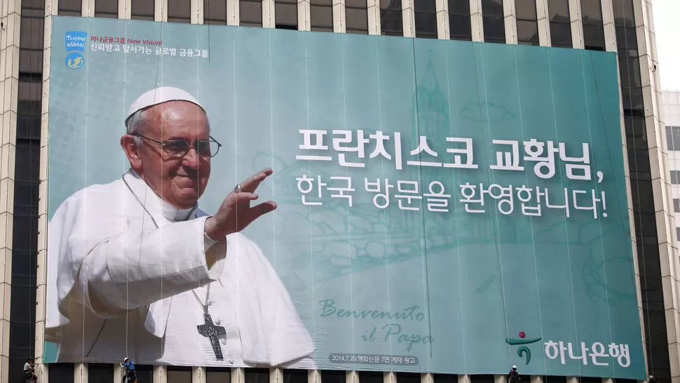 HACIA COREA. Trabajadores colocan un cartel gigante, en Seúl, donde esperan la llegada del Pontífice. REUTERS