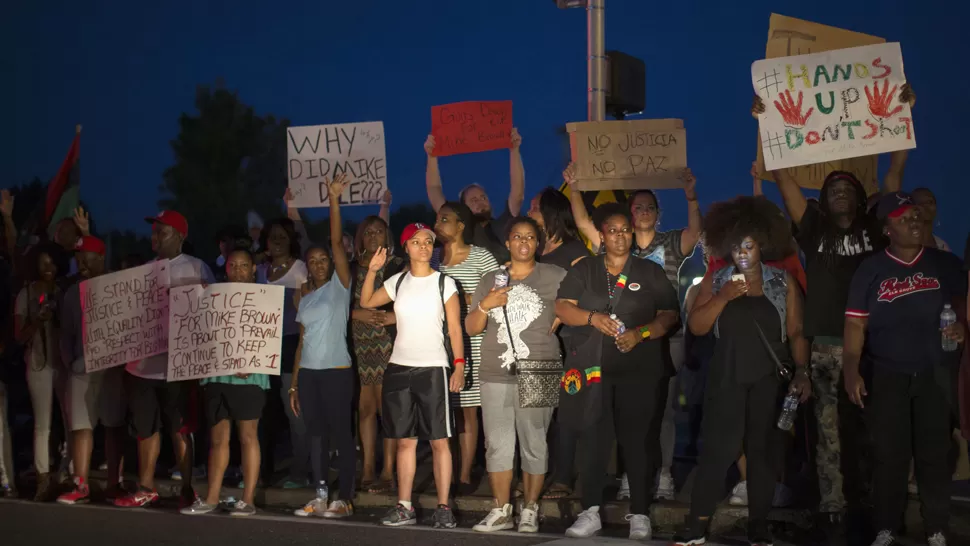 MANOS ARRIBA, NO DISPAREN. Con carteles y actitud pacífica, los manifestantes marcharon anoche en Ferguson. REUTERS