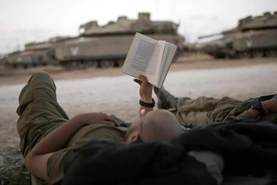 LECTURA. La tregua de cinco días se prolongó ayer en la Franja de Gaza. Cerca de la frontera, soldados israelíes descansan a la espera de órdenes. credito