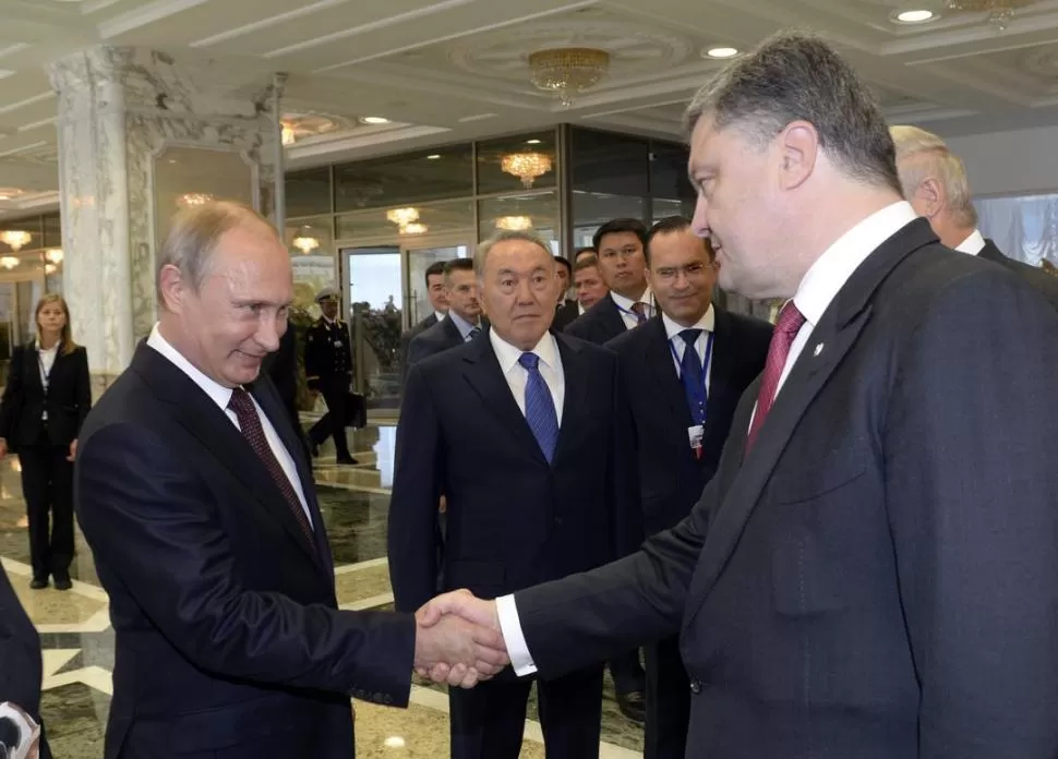 SALUDO. Putin y Poroshenko se dan la mano ante la mirada de Nazarbáyev. reuters