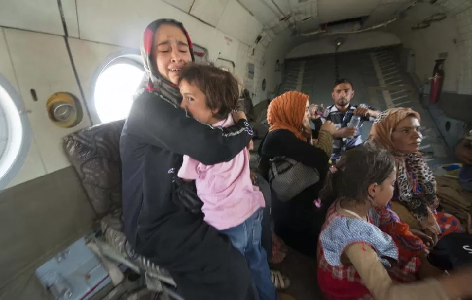 EN EL NORTE. Una mujer abraza a su hijita, tras ser evacuada junto a otras familias en un helicóptero iraquí de Amerli, un pueblo asediado por el ISIS. REUTERS
