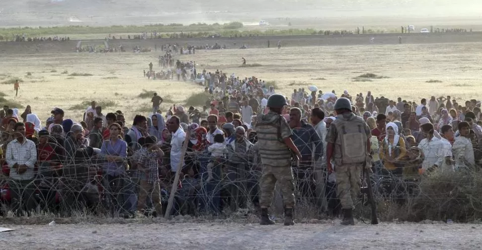 LA FRONTERA. Una larga fila de kurdos provenientes de Siria esperan ingresar a la provincia turca de Sanliurfa. reuters