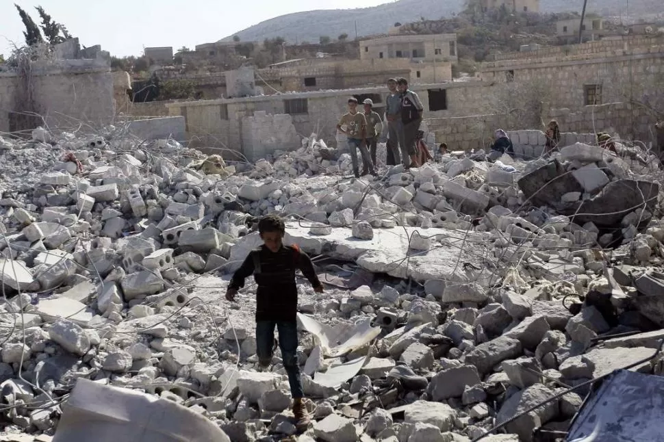 EN KFREDRIAN. Los niños observan la destrucción de una vivienda, tras el ataque de aviones de EEUU en Siria. reuters