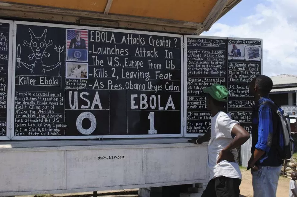 MONROVIA. Transeúntes de la capital de Liberia leen noticias escritas en un pizarrón. USA 0, Ébola 1, dice, para marcar el primer caso en EEUU. reuters