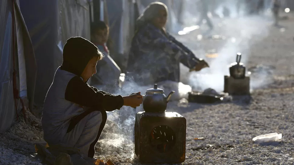 DESPLAZADOS. Un niño kurdo prepara té en un campo de refugiados que escaparon de la guerra en Siria. REUTERS
