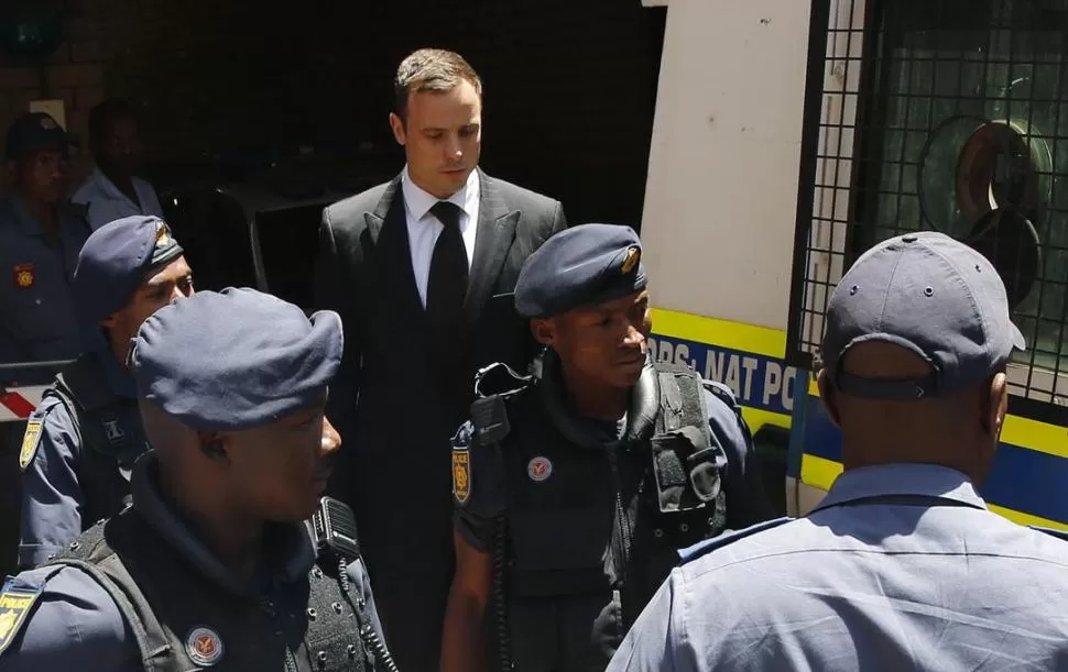 FUERTE CUSTODIA. Pistorius sale de la corte rodeado de policías, luego de escuchar la sentencia de parte de la jueza Masipa. 
