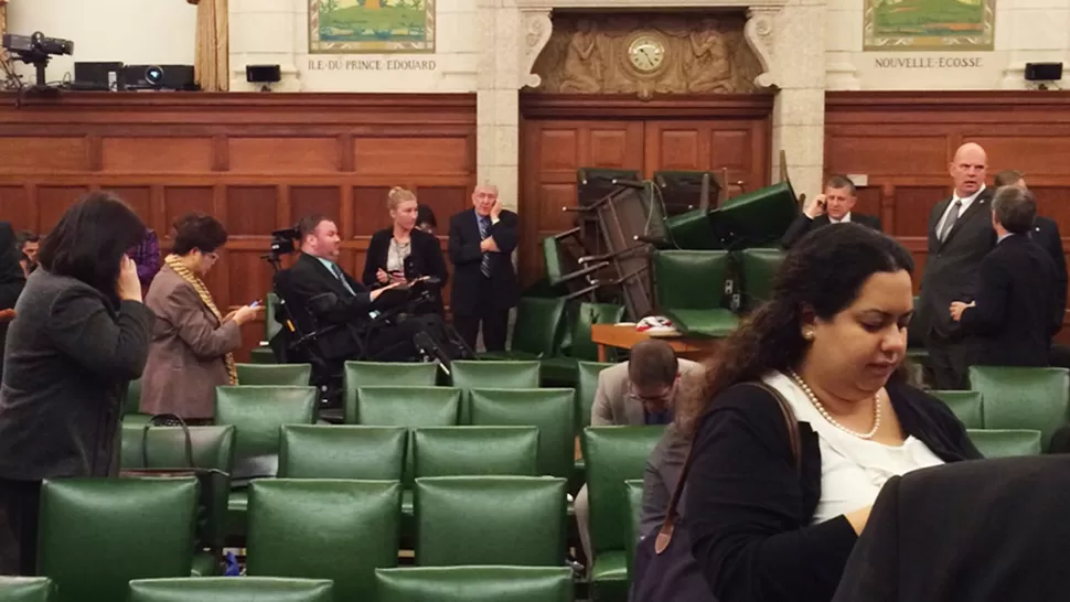 TENSIÓN. Los legisladores canadienses se reacomodan en el recinto, tras el ataque. Apilaron sillas para cubrirse. REUTERS