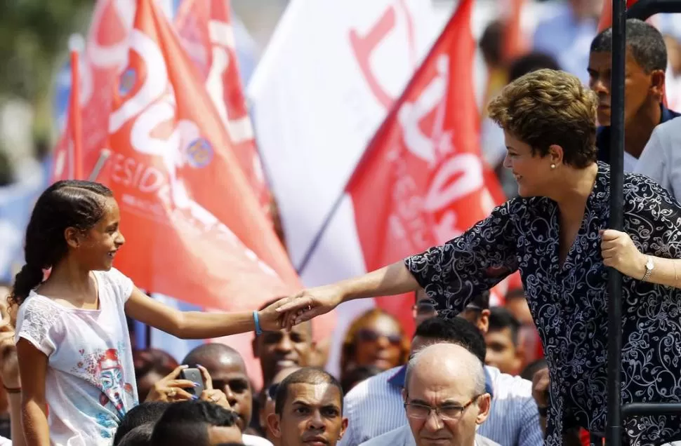NUEVA IGUAZÚ. Rousseff saluda a una niña, durante una caravana que realizó por la ciudad próxima a Río. reuters