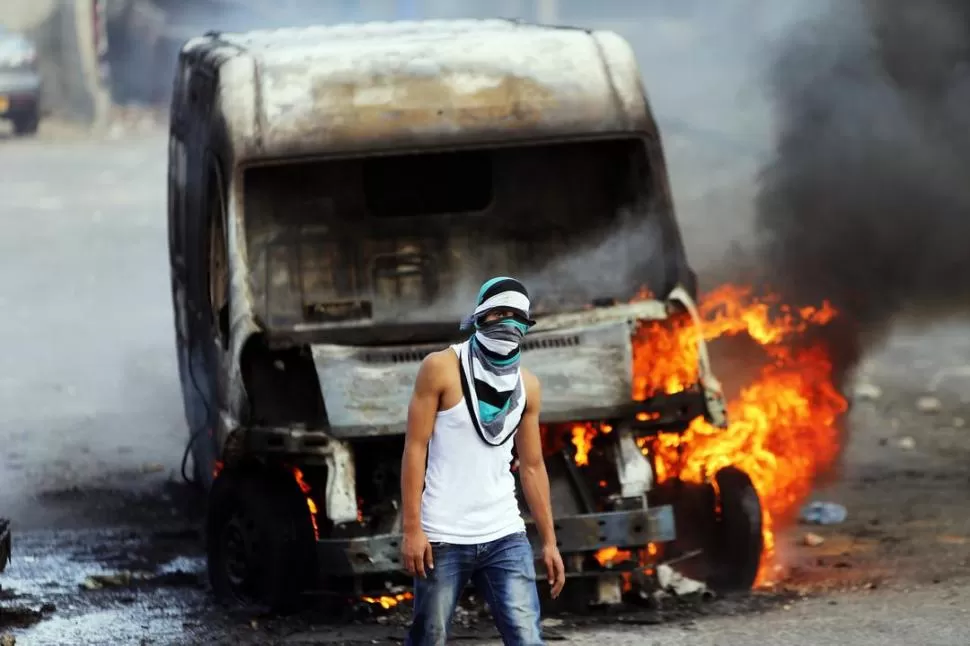 REACCIÓN. Un joven palestino camina por delante de un auto incendiado. reuters