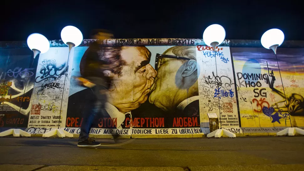 NUEVAS LUCES. Un dibujo, que muestra al ex líder soviético Leonid Brezhnev besando a su homólogo de Alemania Oriental, Erich Honecker, está pintado en la parte más amplia que queda en pie del Muro de Berlín. reuters