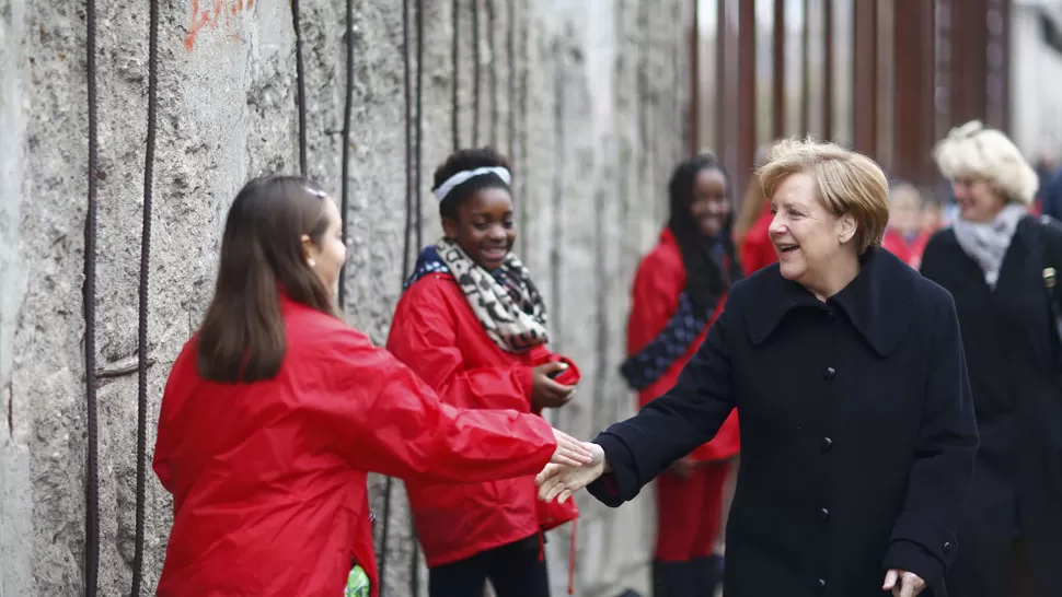 CELEBRACIÓN. Angela Merkel saluda a unos chicos en uno de los actos a 25 años de la caída del Muro de Berlín. REUTERS