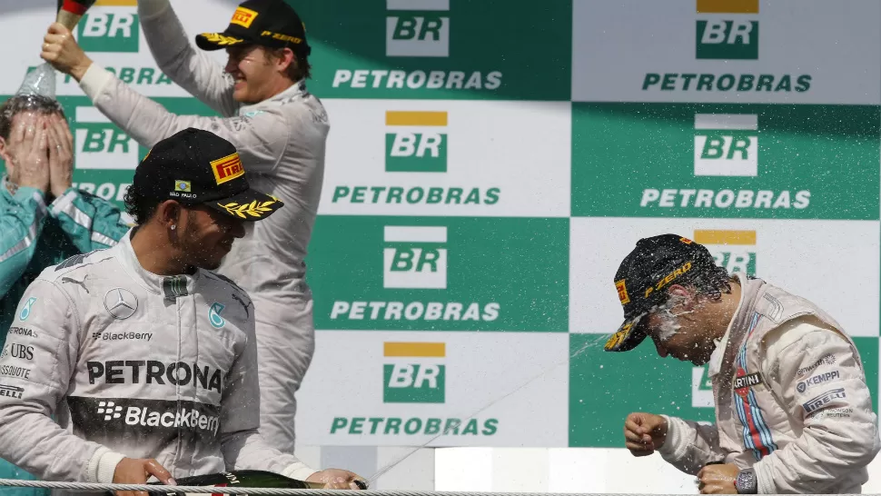 FESTEJO EN EL PODIO. Lewis Hamilton, Felipe Massa y Nico Rosberg celebran con la tradicional bañada de champagne tras la carrera de Interlagos. REUTERS