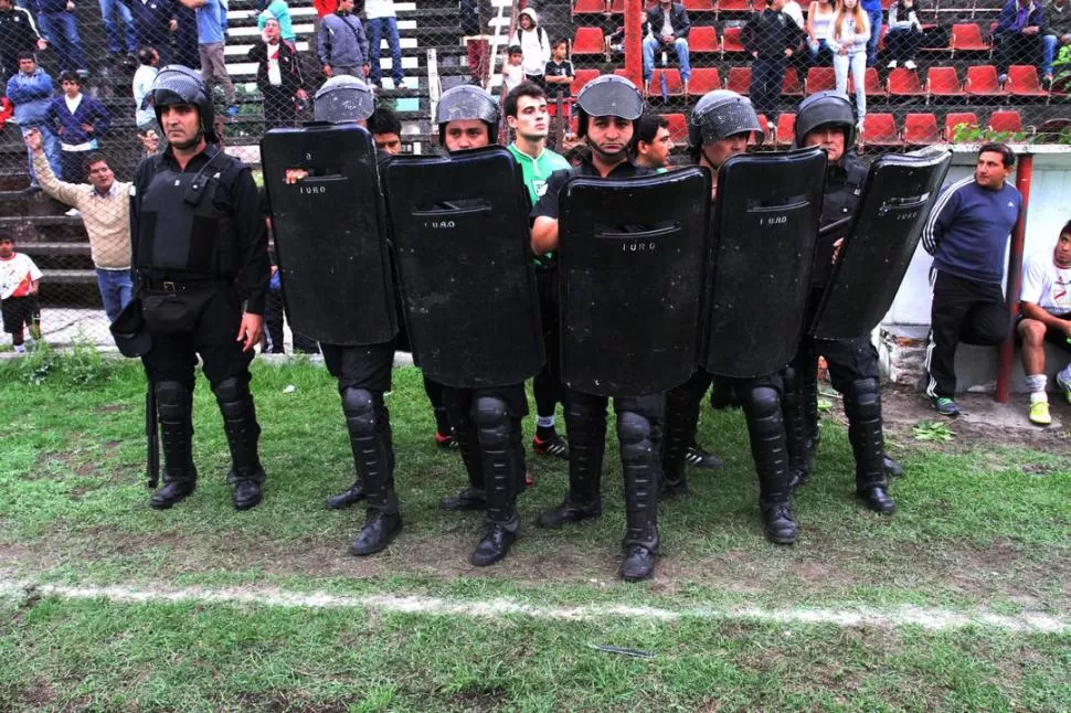 UNA ESCENA DE TERROR. Un grupo de policías de Infantería custodia al árbitro Mauricio Martín y a sus colaboradores para que no sean agredidos por los jugadores de Deportivo Aguilares. 