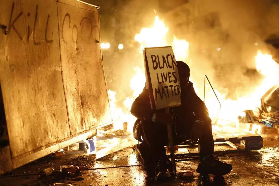 DESAFÍO. Un joven negro que protestó en Ferguson aparece entre las llamas. fotos reuters