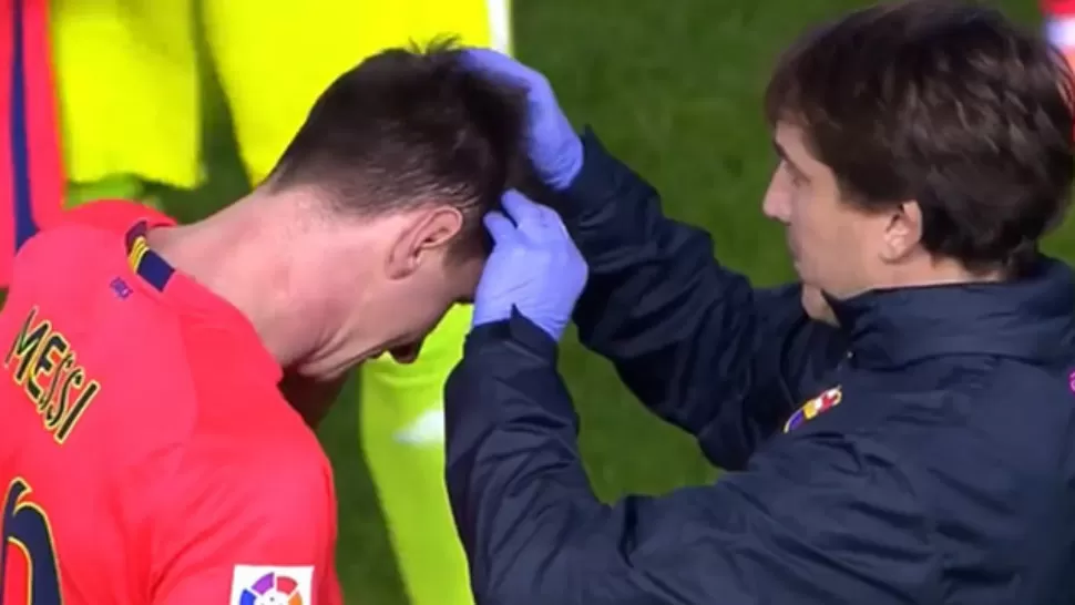 HERIDO. Lionel Messi es atendido por el médico de Barcelona, tras el botellazo que recibió en su cabeza. 