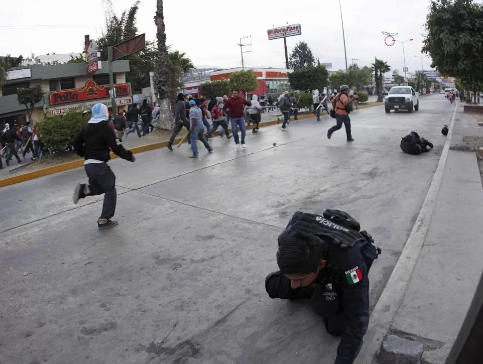 AL SUELO. Dos policías (a la derecha) caen heridos por los docentes y estudiantes con los que se enfrentaron. reuters