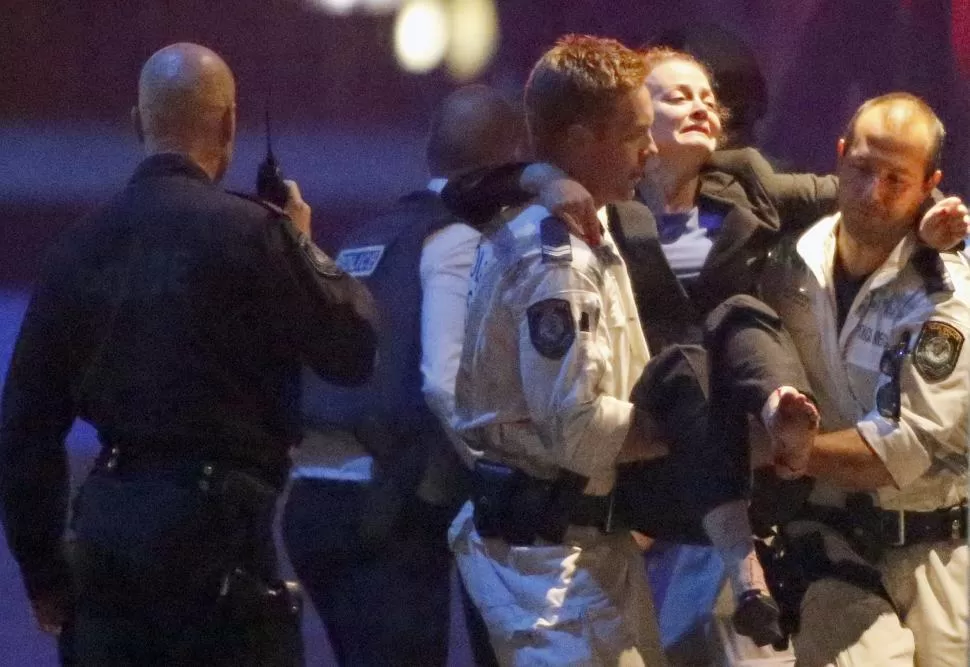 RESCATE. La policía traslada una mujer herida, durante la balacera en el Café Lindt del centro de Sydney. Un iraní había tomado 17 rehenes en el lugar. reuters