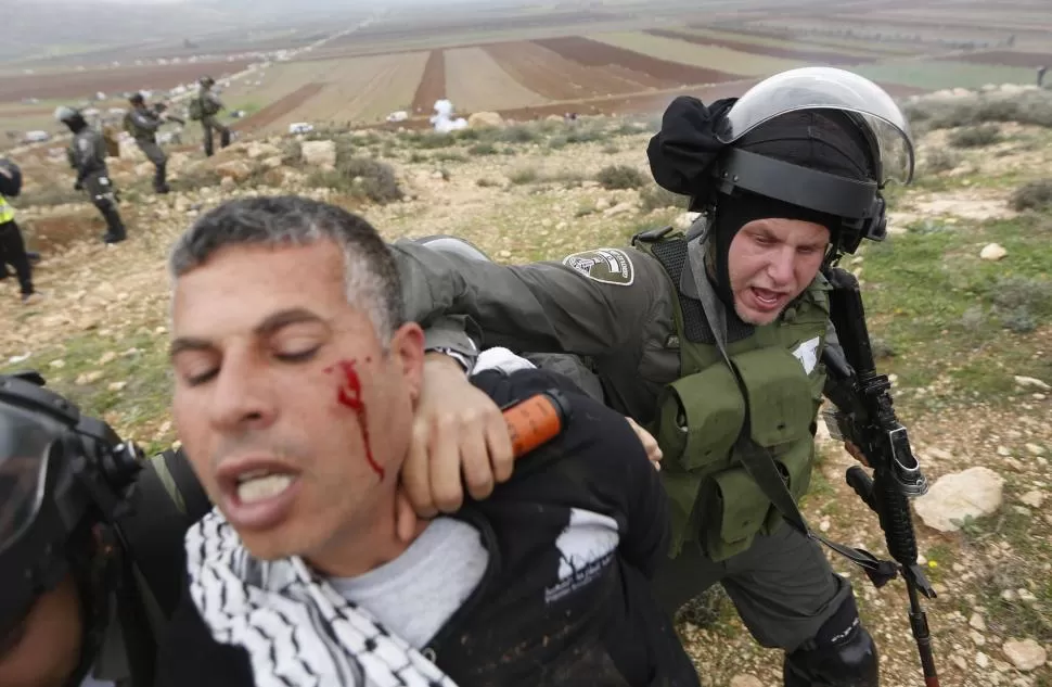 CERCA DE RAMALAH. Un policía israelí fronterizo detiene a un palestino, que participaba de una protesta. reuters