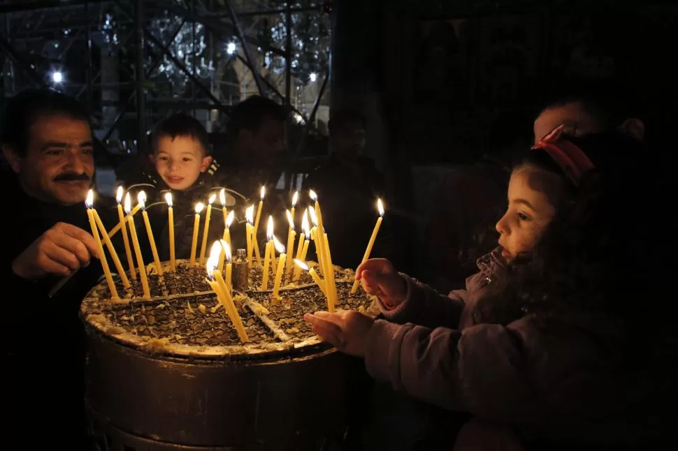 ILUMINANDO LAS FIESTAS. Visitantes encendían velas ayer en la Iglesia de la Natividad, en la ciudad cisjordana de Belén, un sitio que es venerado por los cristianos como el lugar mismo donde aconteció el nacimiento de Jesús. reuters