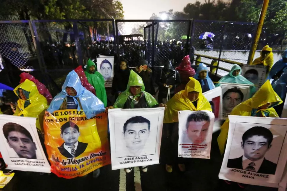 A TRES MESES. Frente a la residencia presidencial de México, familiares de los estudiantes desaparecidos muestran sus fotos durante una protesta. reuters