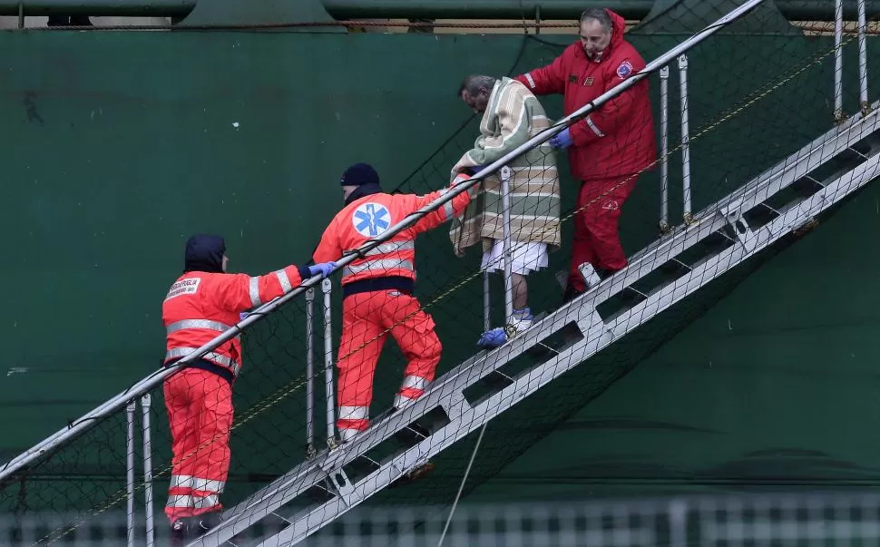 EN BARI. Un pasajero del ferry es ayudado a salir del barco que lo rescató. reuters