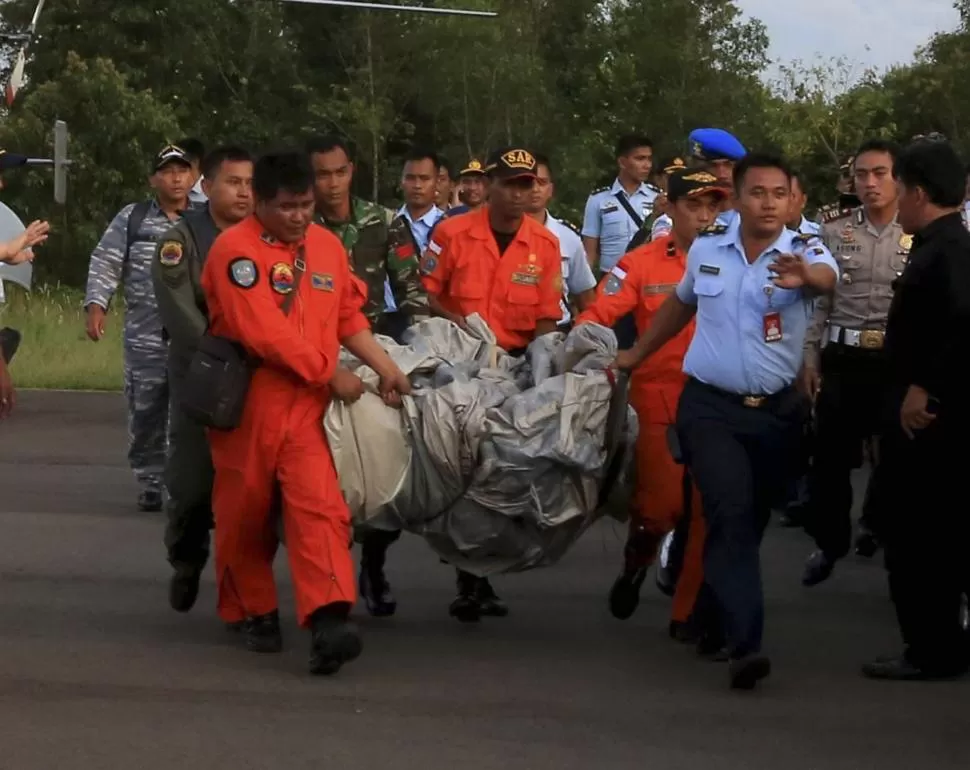 RESCATE. Operarios trasladan restos del avión siniestrado, que fueron recogidos en el mar de Java, cerca de la costa Sur de la isla de Borneo.  
