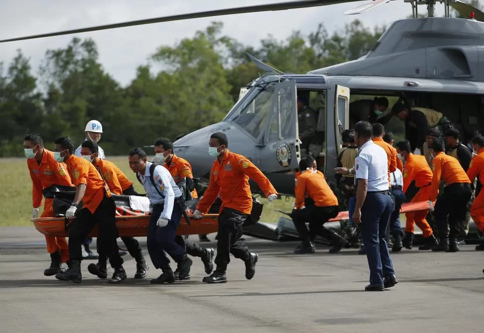 TRASLADO. Socorristas trasladan desde un helicóptero el cuerpo de uno de los pasajeros recuperados del mar. Todo Indonesia llora el desastre. reuters