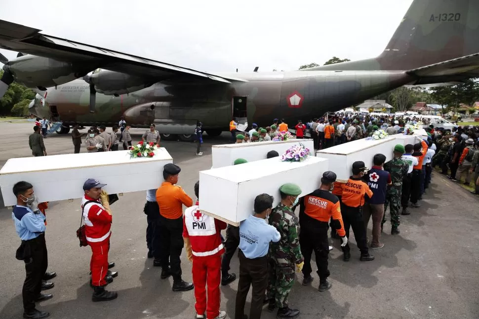 EN SURABAYA. Socorristas trasladan féretros con los cuerpos rescatados de los pasajeros, que fueron depositados por los aviones de transportes. FOTO DE REUTERS