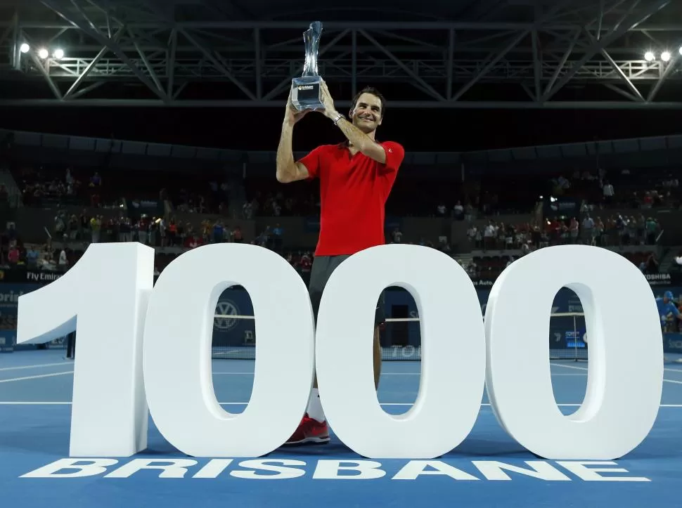 UN SÍMBOLO. Roger Federer muestra orgulloso el trofeo y posa con el número 1.000 gigante que los organizadores prepararon para homenajear su histórica marca. reuters