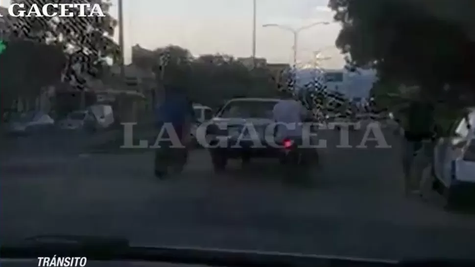 Dos motos, sin patente, empujan un automóvil por la avenida Roca