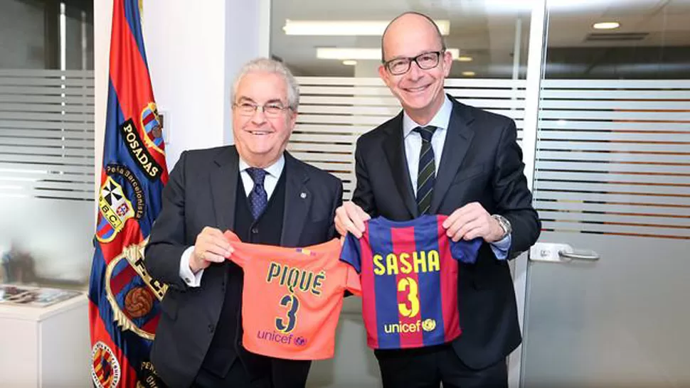 NUEVO CULE. El abuelo y un dirigente de Barcelona sostienen las camisetas que el club le regalará al pequeño, que tendrá el número 155.629 como socio. FOTO TOMADA DE FCBARCELONA.ES
