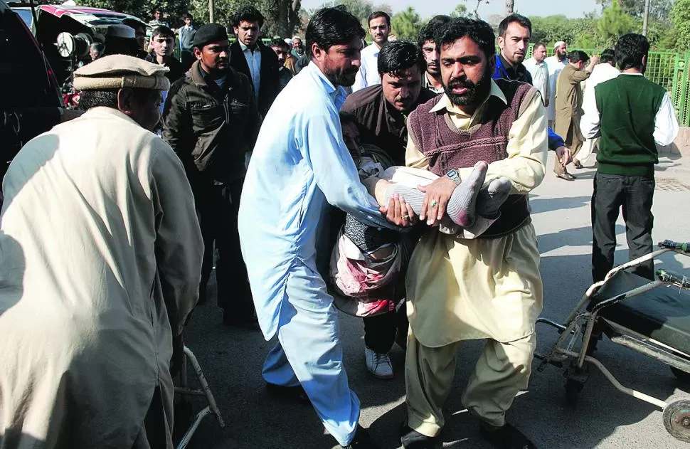 ENSANGRENTADO. Paquistaníes intentan asistir a las víctimas del ataque. reuters