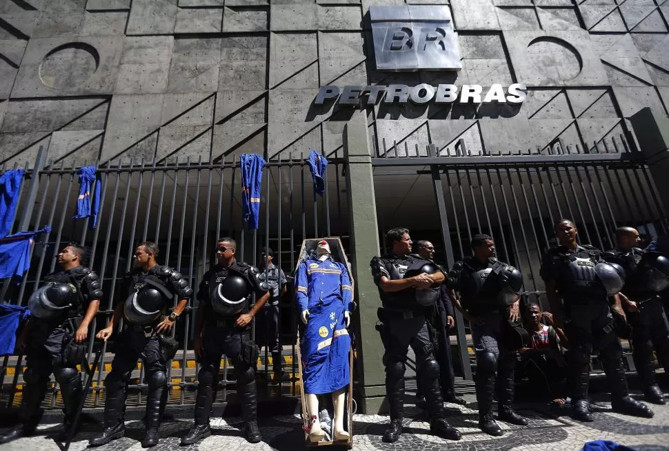 HACIA EL FIN. La sede de Petrobrás fuertemente custodiada por la protesta de trabajadores despedidos, que representaron su situación con un ataúd. reuters