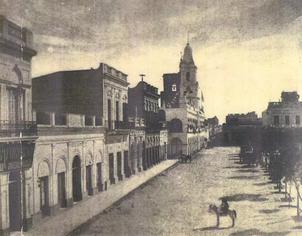 VEREDA DEL CABILDO. Este aspecto tenía, hacia la época de los sucesos de 1893, la primera cuadra de calle 25 de Mayo. Sólo la Casa Padilla (cuarta desde la izquierda) subsiste hoy.
