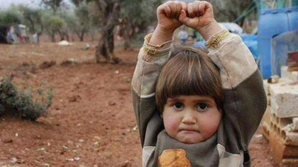 Una niña siria levanta las manos al confundir la cámara con un arma