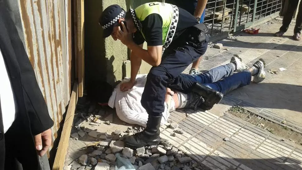 DETENIDO. Un policía pide refuerzos por teléfono mientras sostiene al delincuente en el piso. LA GACETA EN WHATSAPP.
