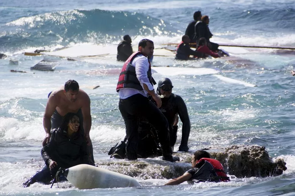 LA ISLA DE RODAS. Personal de la guardia costera griega y lugareños ayudan a rescatar del mar a inmigrantes que llegaban en un barco que encalló. reuters