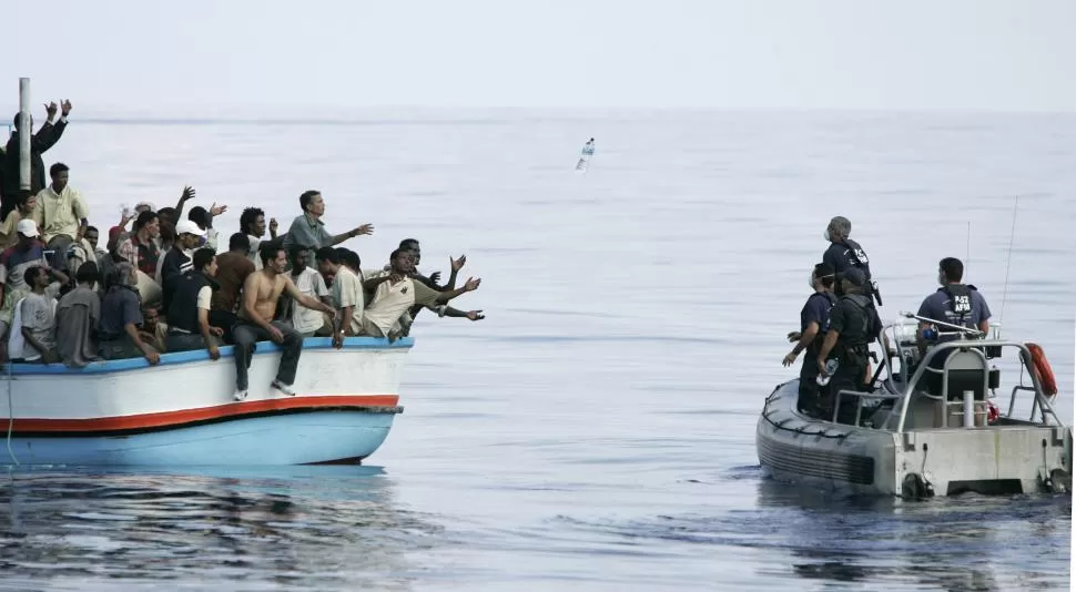 COSTA DE MALTA. Miembros de la guardia costera maltesa arrojan botellas con agua a un grupo de inmigrantes que viajan en un precaria lancha. reuters 