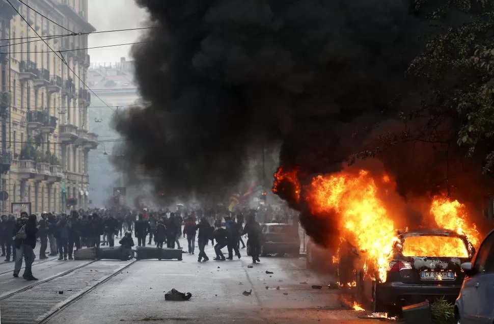 CENTRO DE MILÁN. Un automóvil arde, mientras los manifestantes lanzan piedras contra la Policía, tras el acto de inauguración de la Expo 2015. reuters