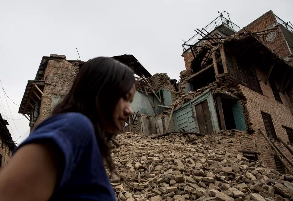 EN LALITPUR. Una mujer camina entre las ruinas de un vecindario cercano a la capital de Nepal, Katmandú. reuters