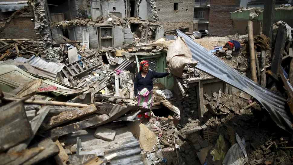DESASTRE. Una mujer escarba entre los escombros de su vivienda. REUTERS