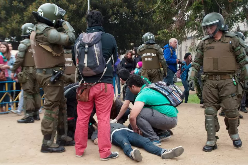 EN VALPARAÍSO. Estudiantes y policías ayudan a uno de los heridos, en el final de la marcha de protesta. reuters