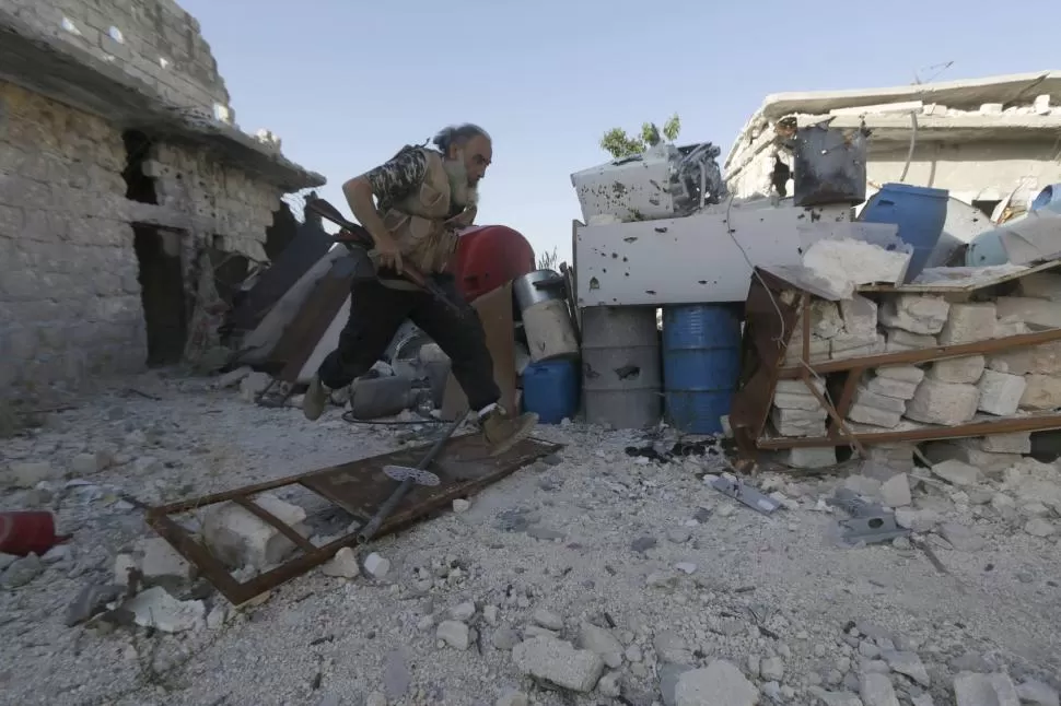 CORRE POR SU VIDA. Un combatiente civil sirio huye ante el ataque del Ejército de Al Assad, en la frontera. reuters
