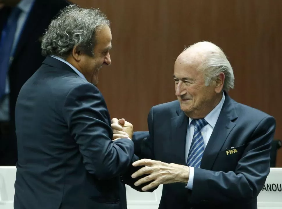 ENFRENTADOS, PERO BIEN EDUCADOS. Michel Platini, presidente de la UEFA, felicita a Joseph Blatter después de haber sido reelecto como titular de la FIFA. reuters