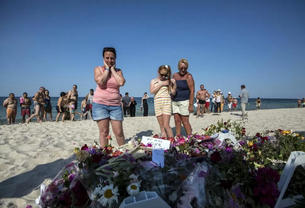 INEXPLICABLE. Viajeros se acercaron a la playa del hotel turístico, llevando flores y orando por las víctimas. reuters