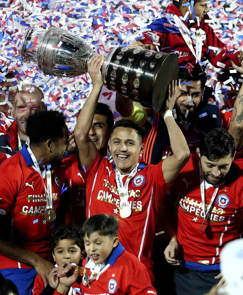 DE VILLANO A HÉROE. Alexis Sánchez, que sonríe para la foto con la copa en la mano, definió el título para los chilenos.  efe