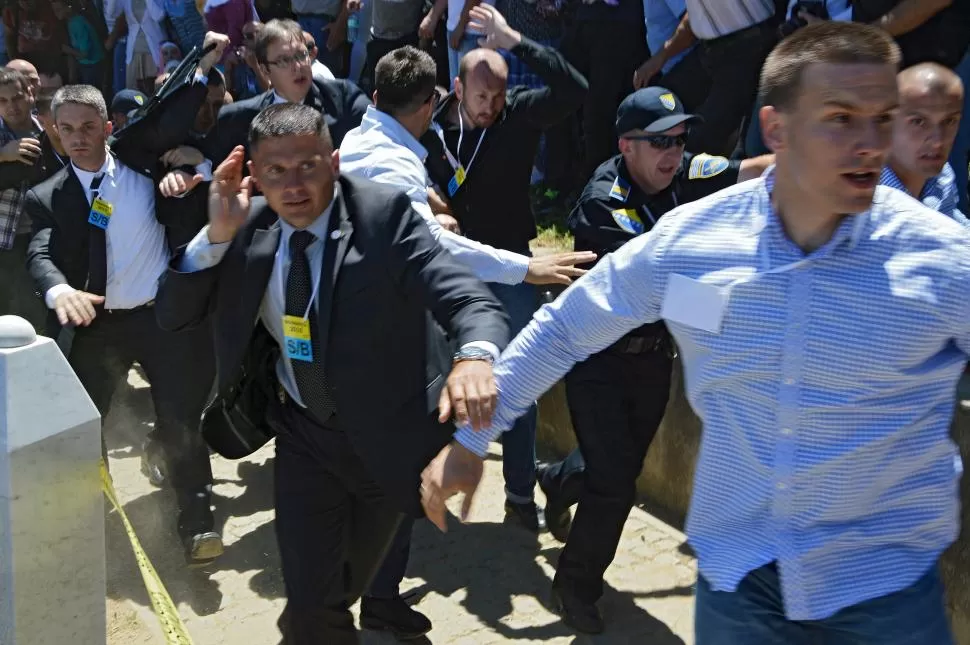 PIEDRAS. Guardaespaldas protegen al primer ministro serbio, Aleksandar Vicic (de anteojos), que fue atacado a pedradas por asistentes al acto. reuters