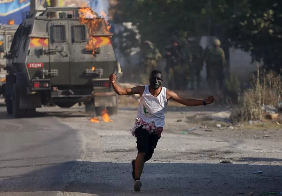 MÁS INCIDENTES. El joven palestino huye, luego de lanzar un cóctel molotov contra un vehículo del ejército israelí, en las proximidades de Ramalah. reuters