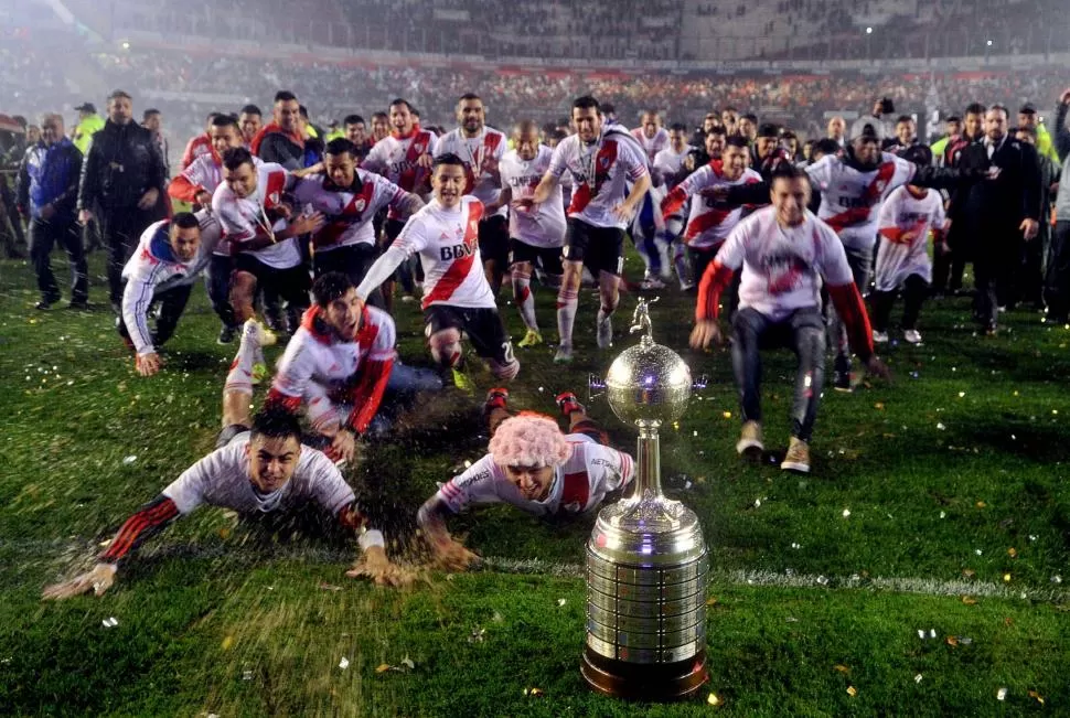 LA COPA SE MIRA Y SÍ SE TOCA... Los futbolistas del “millonario” festejaron la conquista de la Libertadores arrojándose sobre el césped mojado del estadio Monumental de Núñez, que estuvo colmado. télam